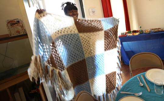Sarah Killingworth shows a blanket she crocheted, during a dinner at her house, Saturday, March 14, 2015.She uses her talents for a business.As part of community outreach, members of Broadway United Methodist Church and the community meet for a meal a