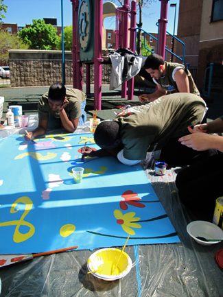 Young men painting a large poster